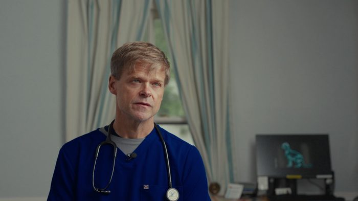 Dr. Reed Hall in blue scrubs with a stethoscope, talking about feline wellness exams